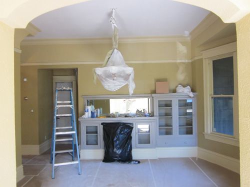 An empty room with a ladder and a chandelier hanging from the ceiling