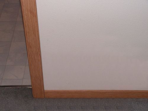 A white wall with a wooden trim in a room.