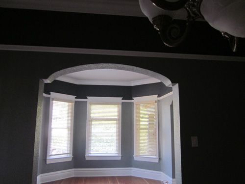 An empty room with a bay window and a chandelier