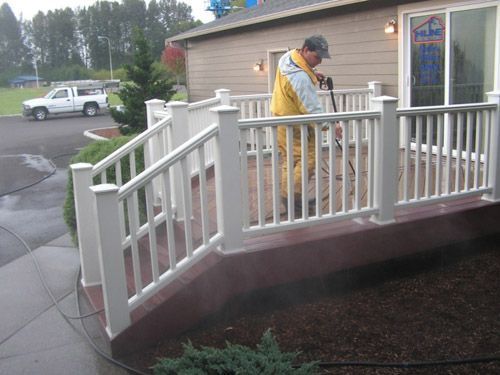 A man is cleaning a deck with a pressure washer