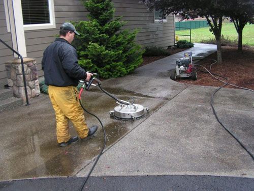 A man is cleaning a driveway with a machine