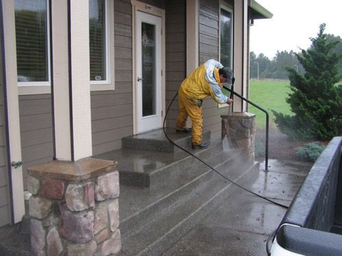 A man is cleaning the steps of a house with a high pressure washer