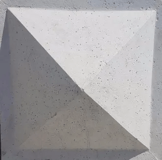 A close up of a white concrete pyramid on a wall.