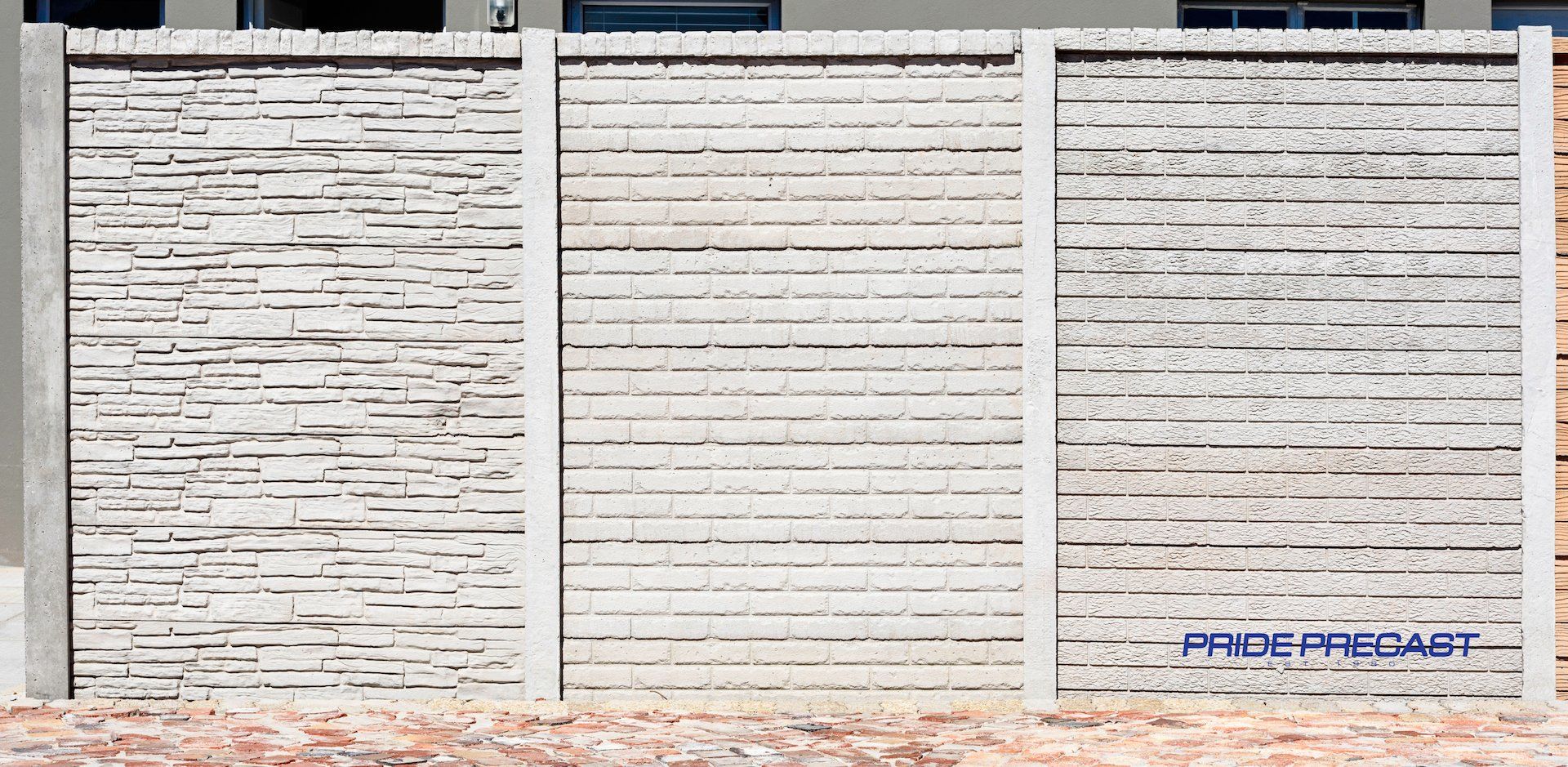 A white fence with black stripes on it is in front of a building.