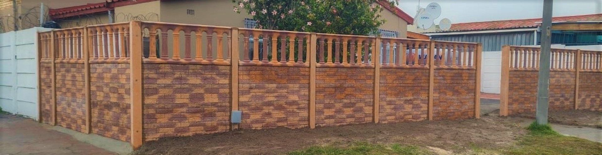 A brick fence with a wooden railing is in front of a house.