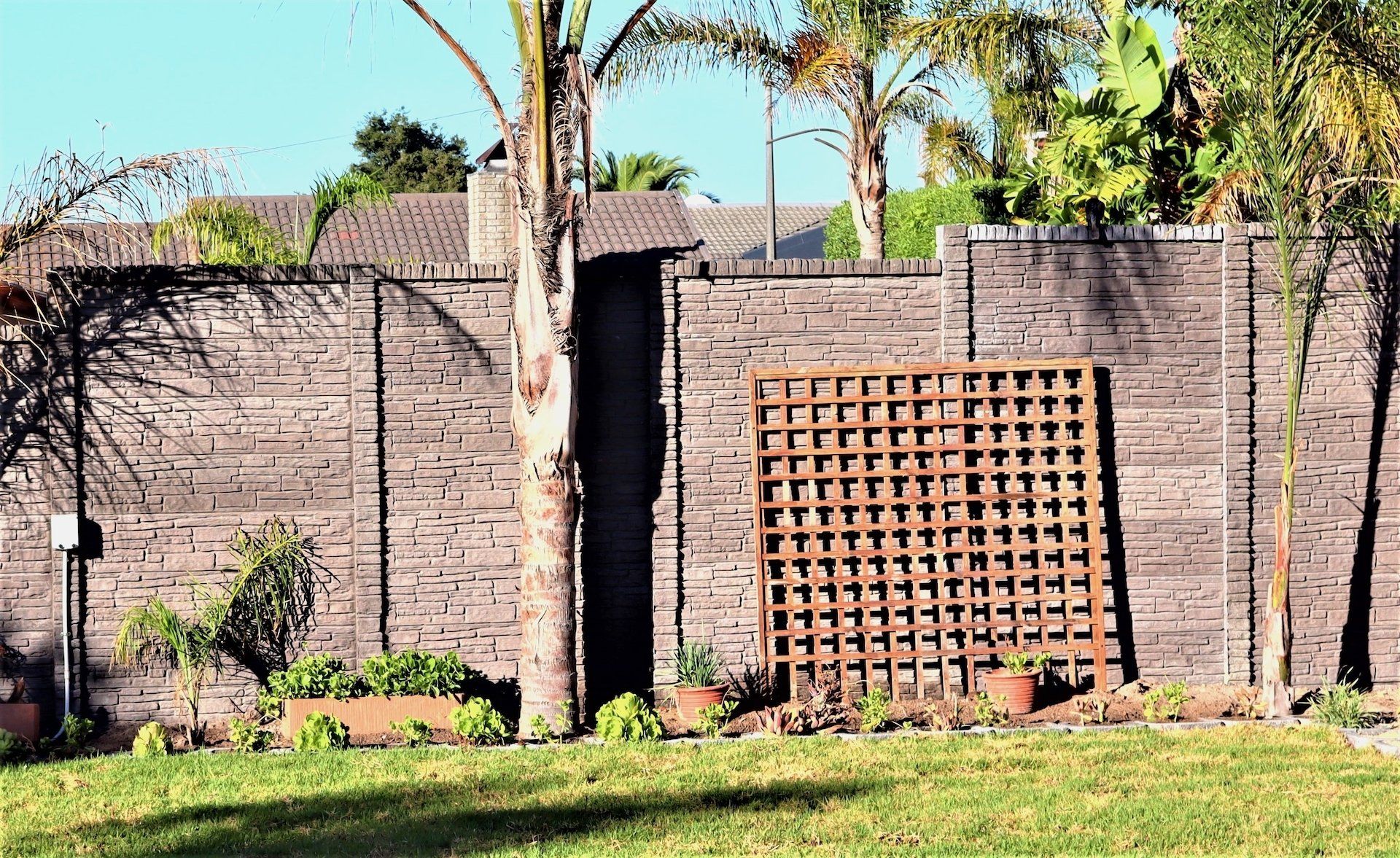 A brick wall with a wooden trellis in the middle of it