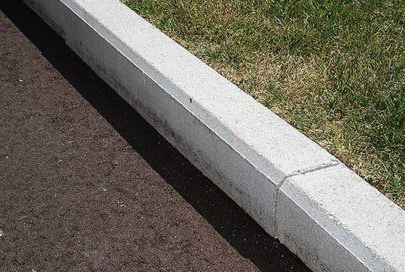 A concrete curb is sitting on the side of a road next to a grassy area.