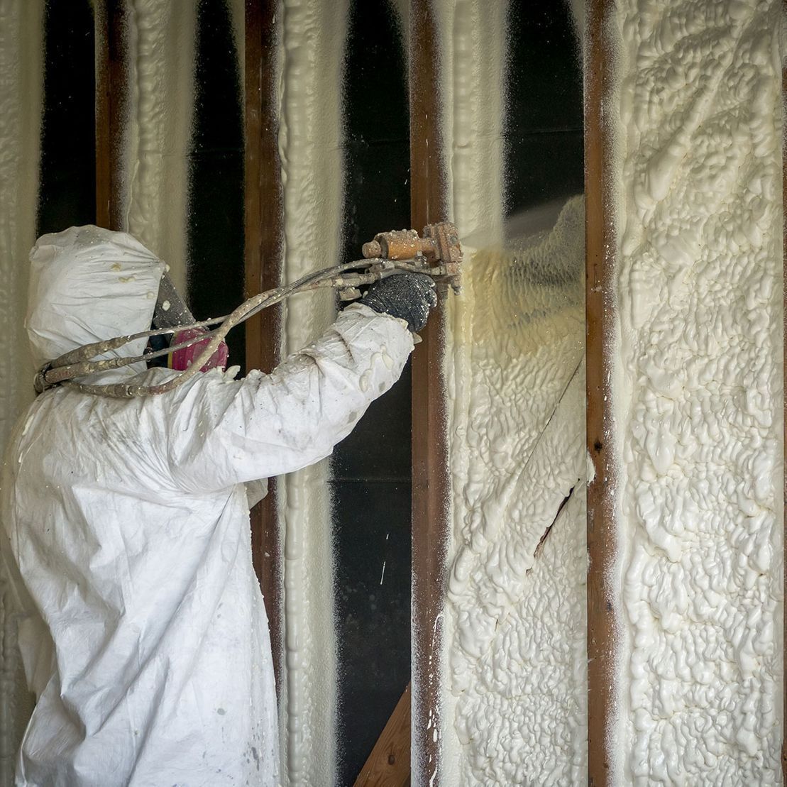 Un homme pulvérise de la mousse sur un mur.