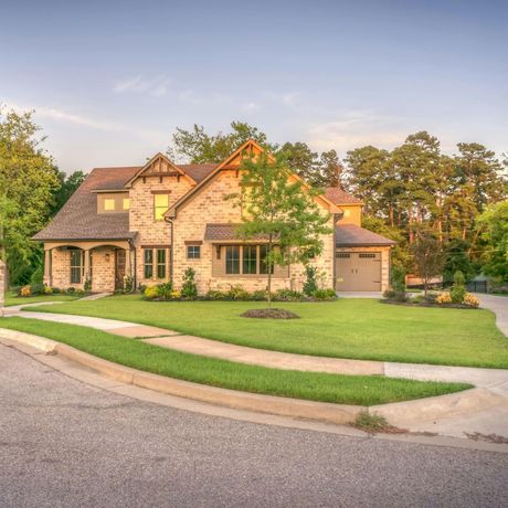 A large brick house with a large lawn in front of it