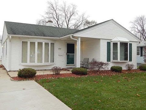 A white house with a black roof and green shutters