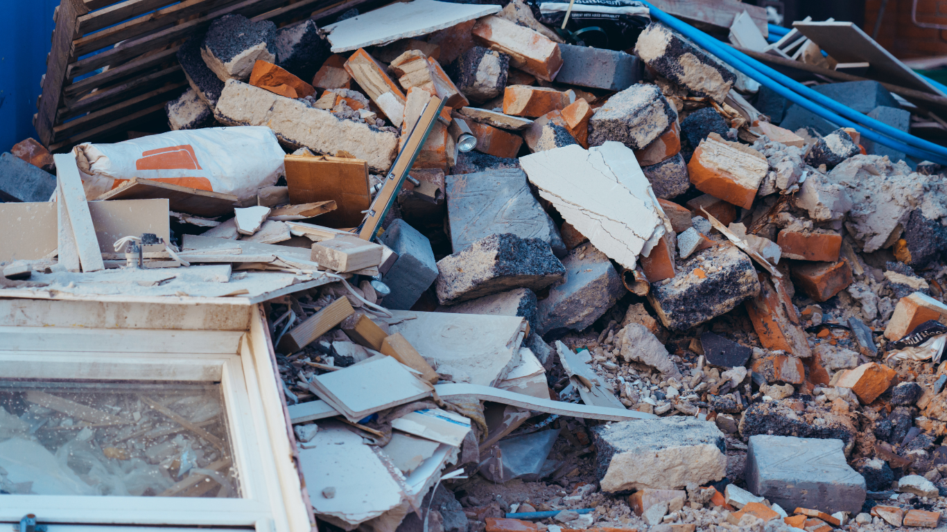 A pile of trash is sitting in the grass in front of a house - debris removal