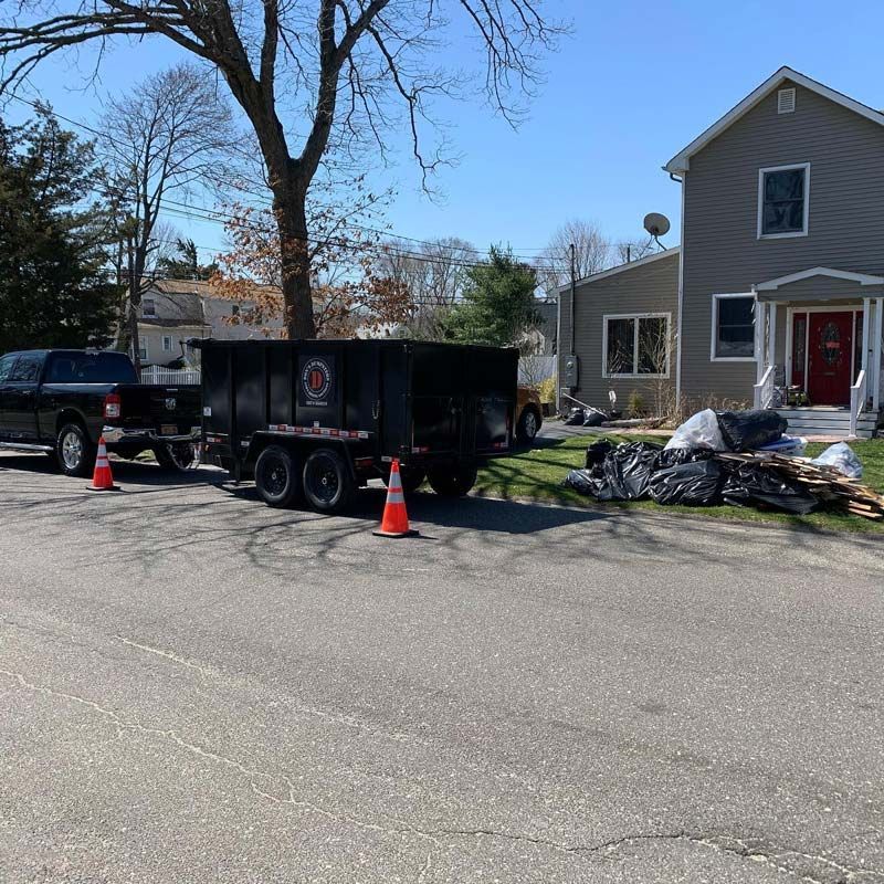 A dumpster is parked in front of a house - Junk Removal Commack