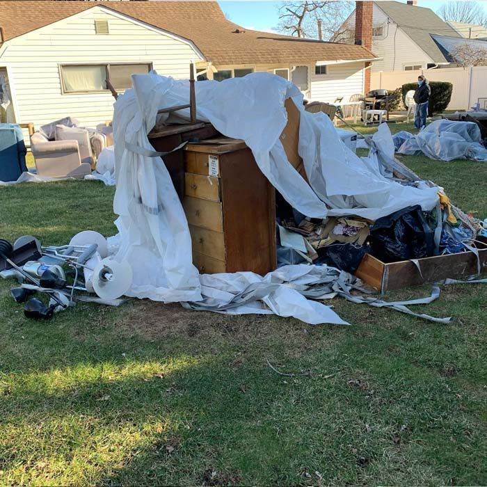 A pile of trash is sitting in the grass in front of a house - debris cleanup