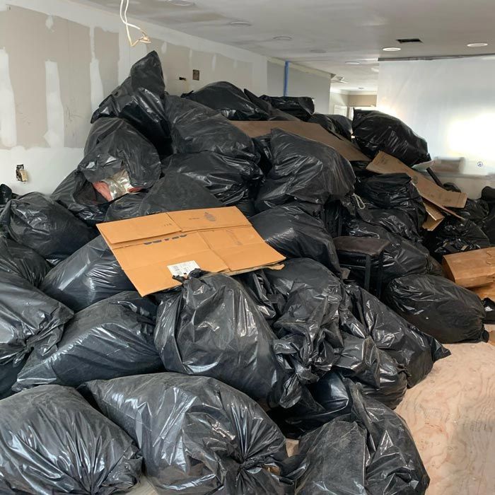 A pile of garbage bags and cardboard boxes in a room - Junk Removal Commack