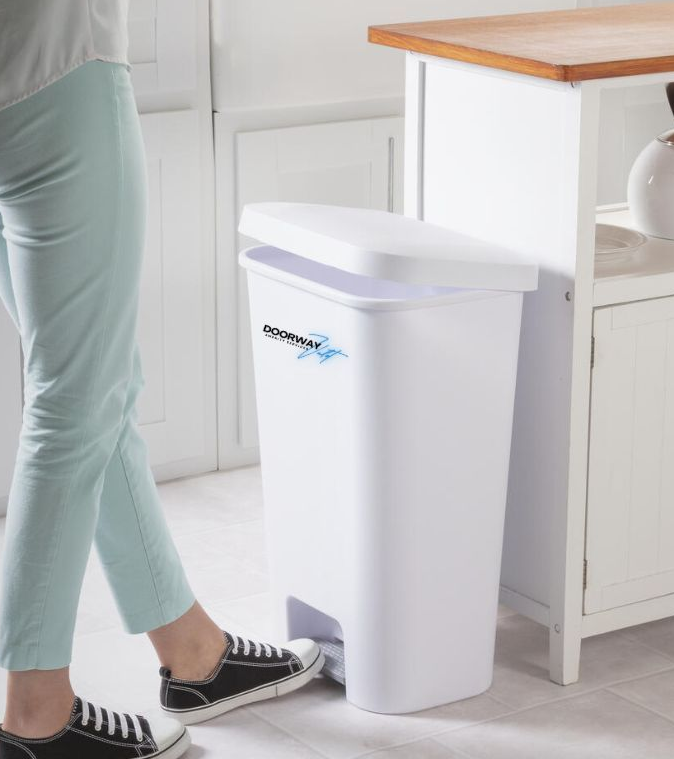 Person stepping on the pedal of a white trash can with a lid in a kitchen.