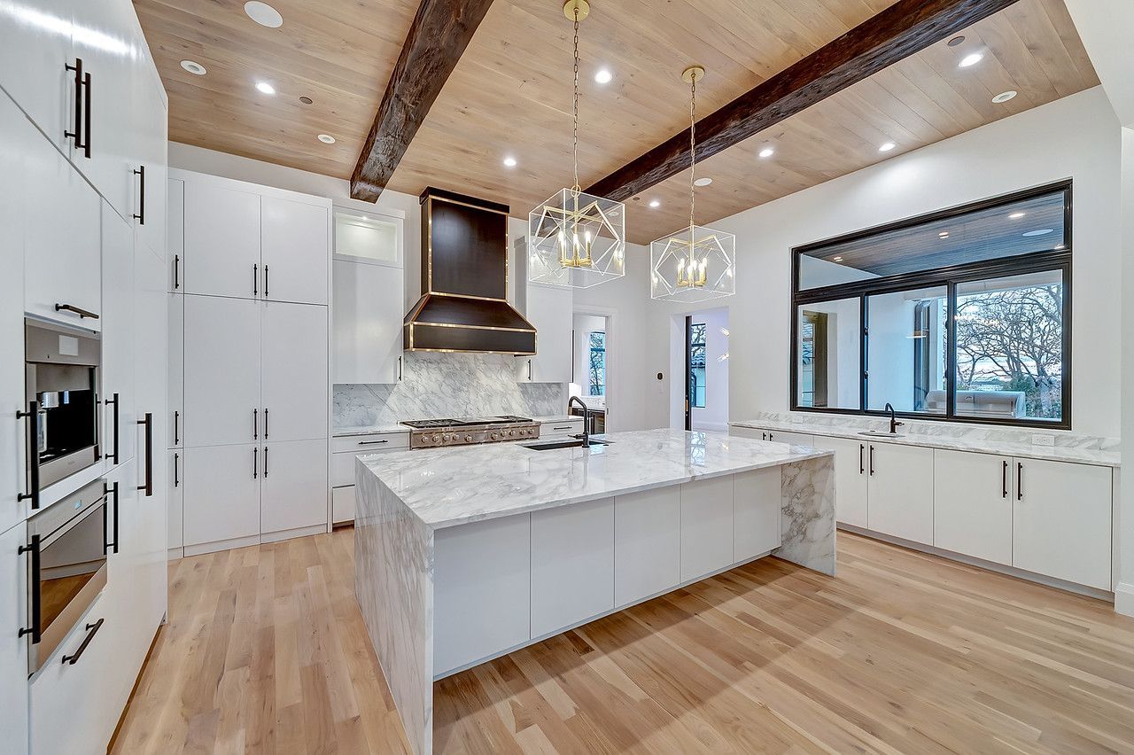  A modern kitchen interior showcasing a Home Renovation with white cabinets, marble countertop