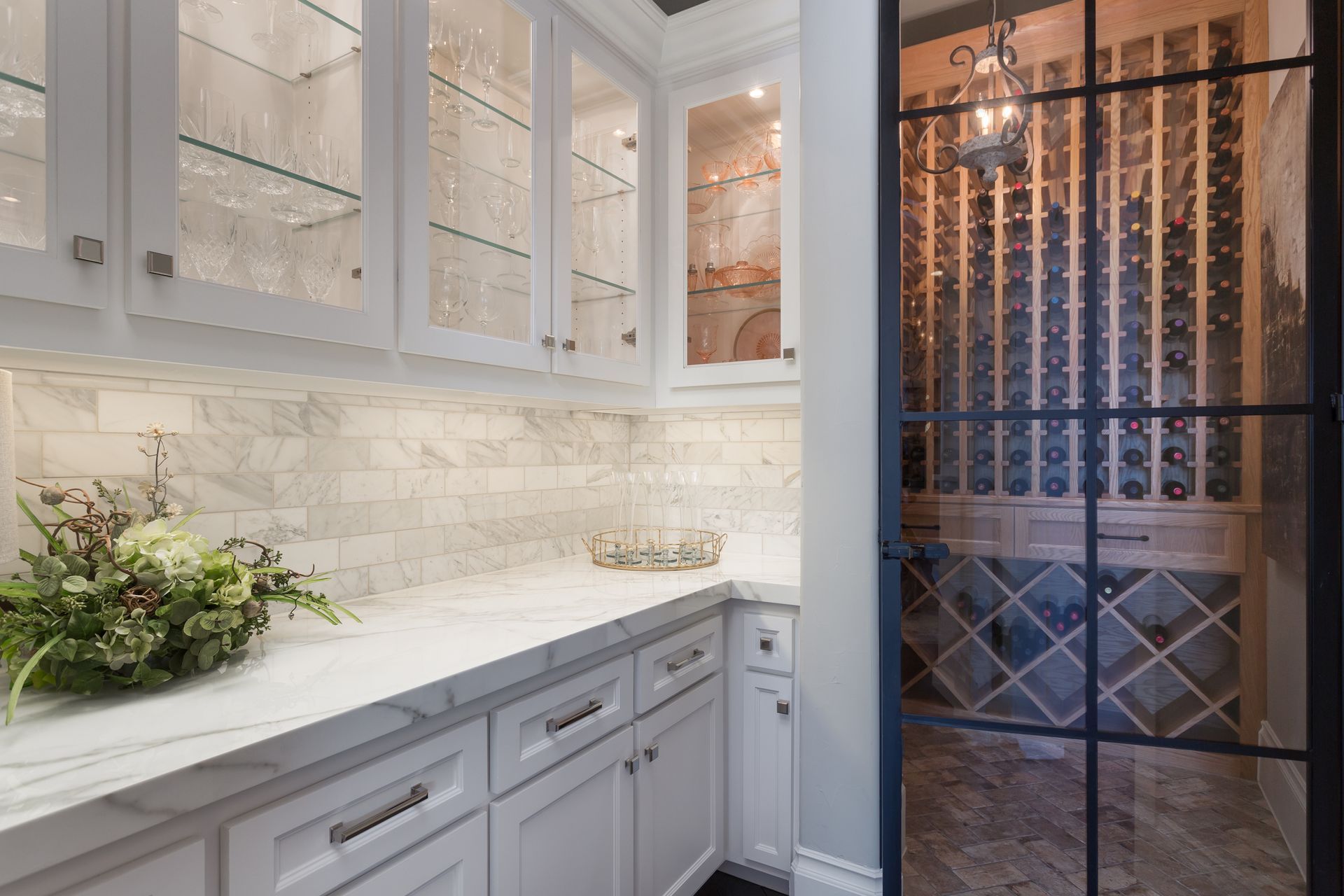 Custom Home Building: Elegant White Kitchen Cabinetry with Glass Doors and Wine Cellar View
