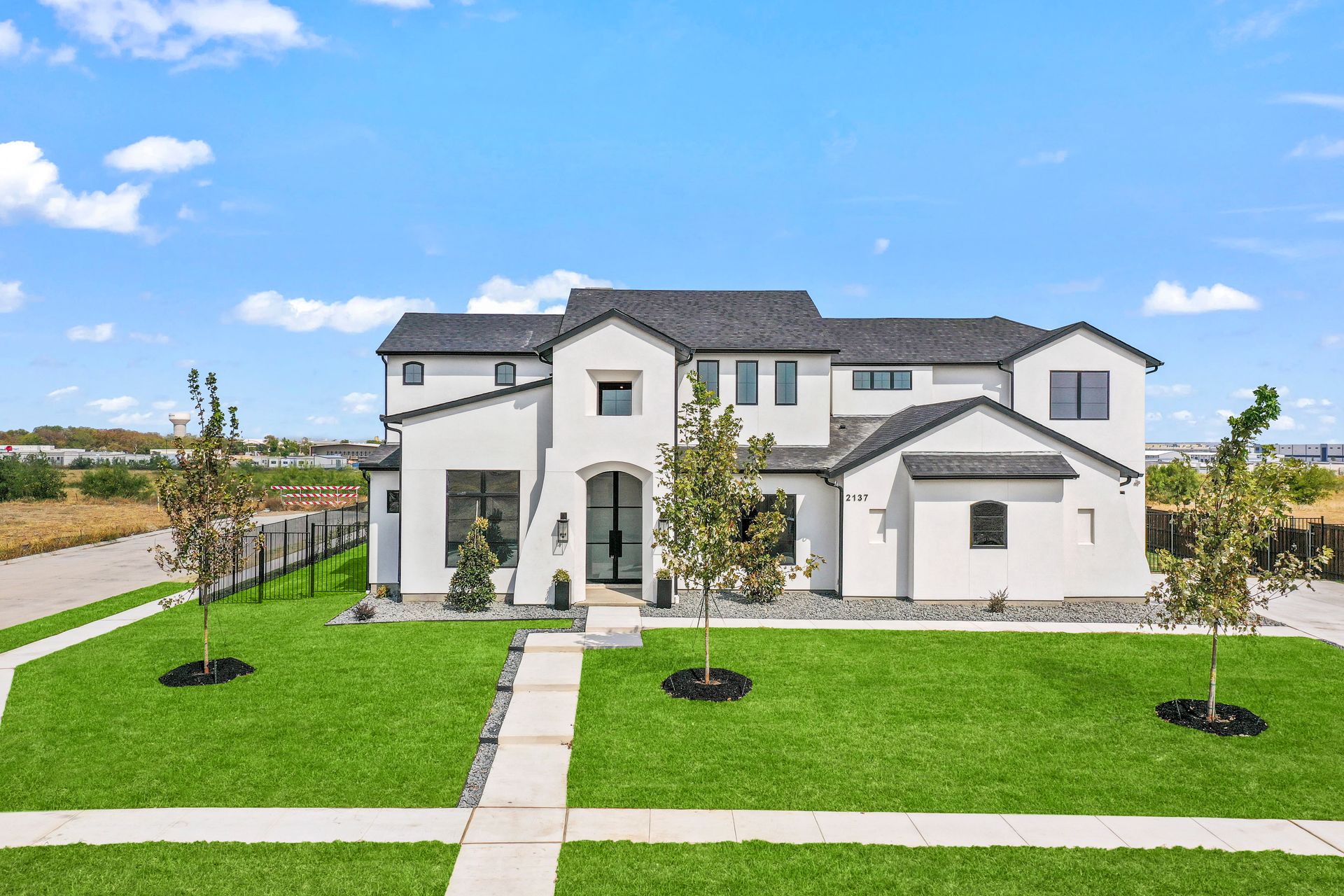 Modern custom home in Southlake, Texas, with a pristine lawn and clear blue sky.
