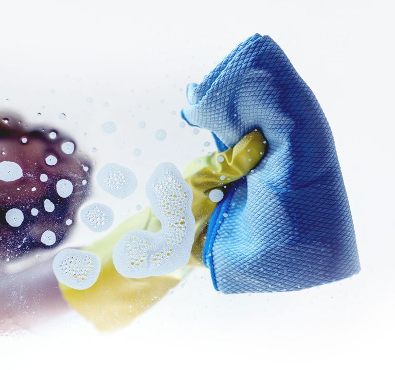 A Person Is Cleaning a Glass with A Blue Cloth — North Coast Commercial Cleaners In Bli Bli, QLD