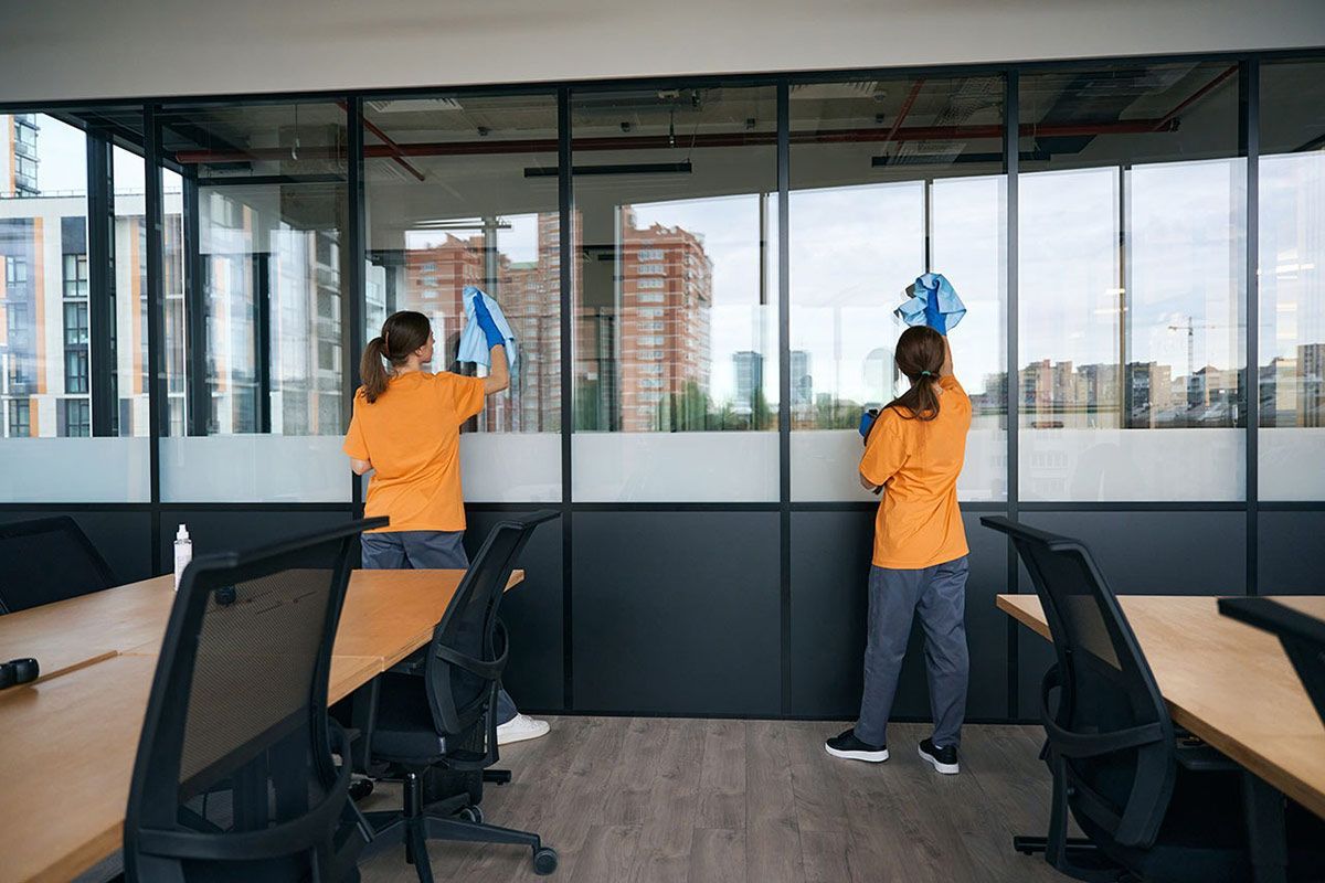 Two Women Are Cleaning Windows in An Office — North Coast Commercial Cleaners In Caloundra, QLD