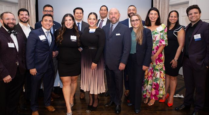 Group of formally dressed people posing at an indoor event, smiling for a group photo.