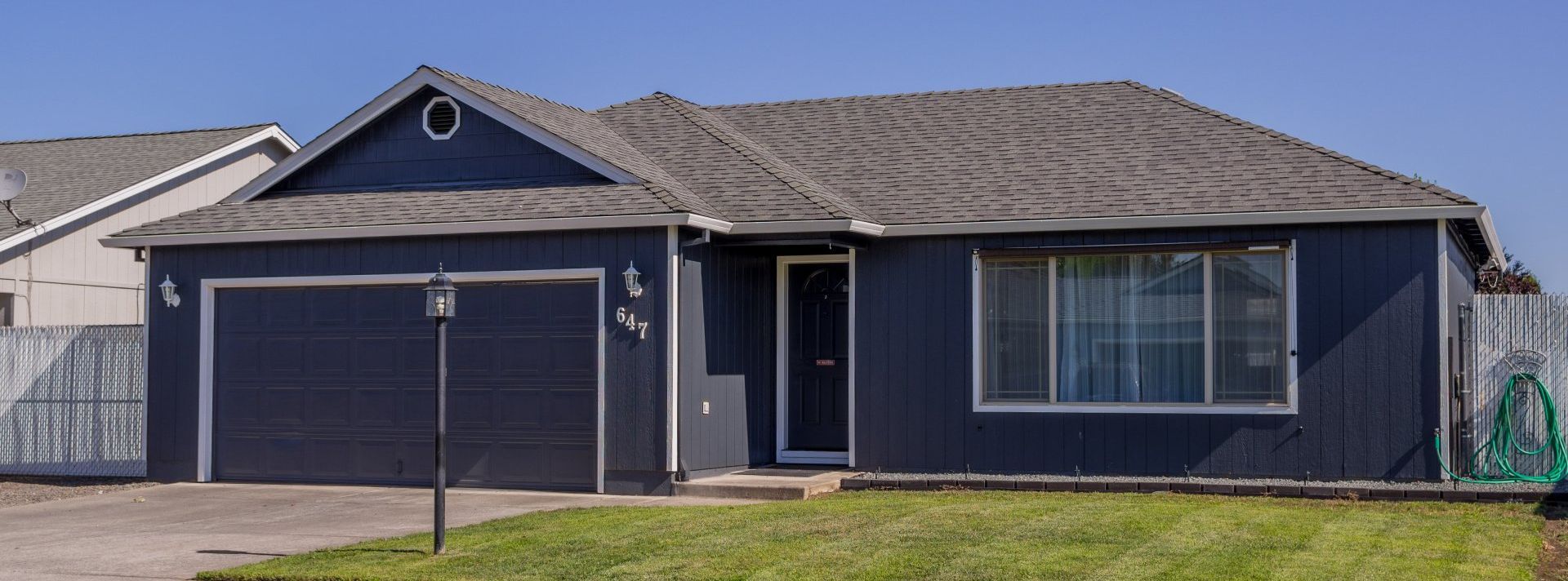 A blue house with a gray roof and a green lawn in front of it.