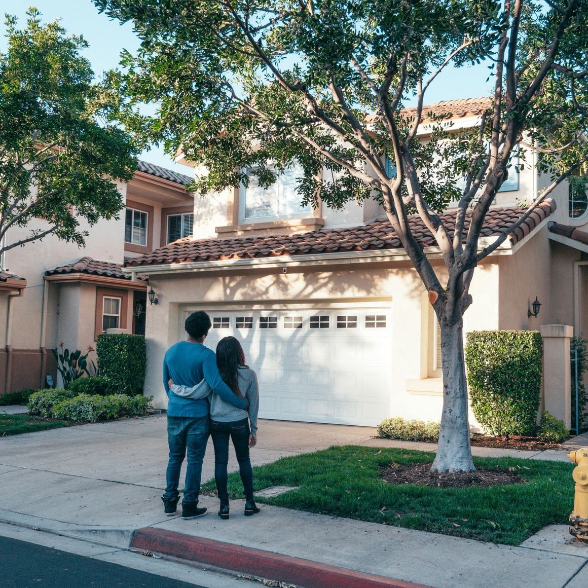 A man and woman are standing in front of a house looking at their new garage door.