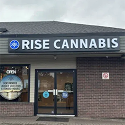 Exterior of RISE Cannabis store with sign, open doors, and brick facade.