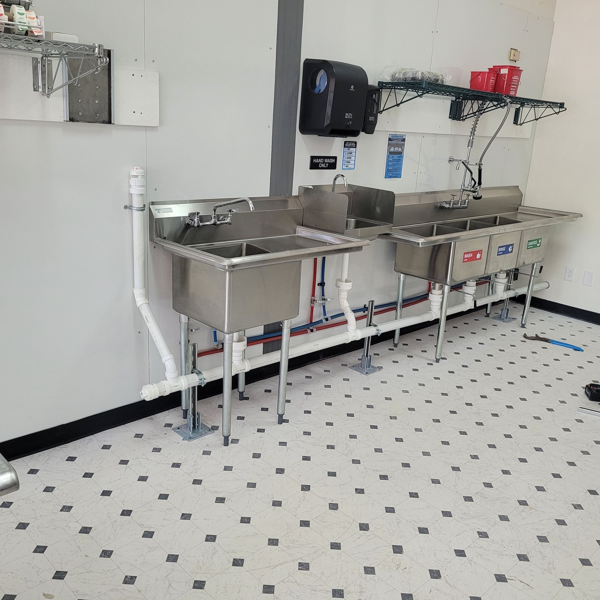 A row of stainless steel sinks in a kitchen