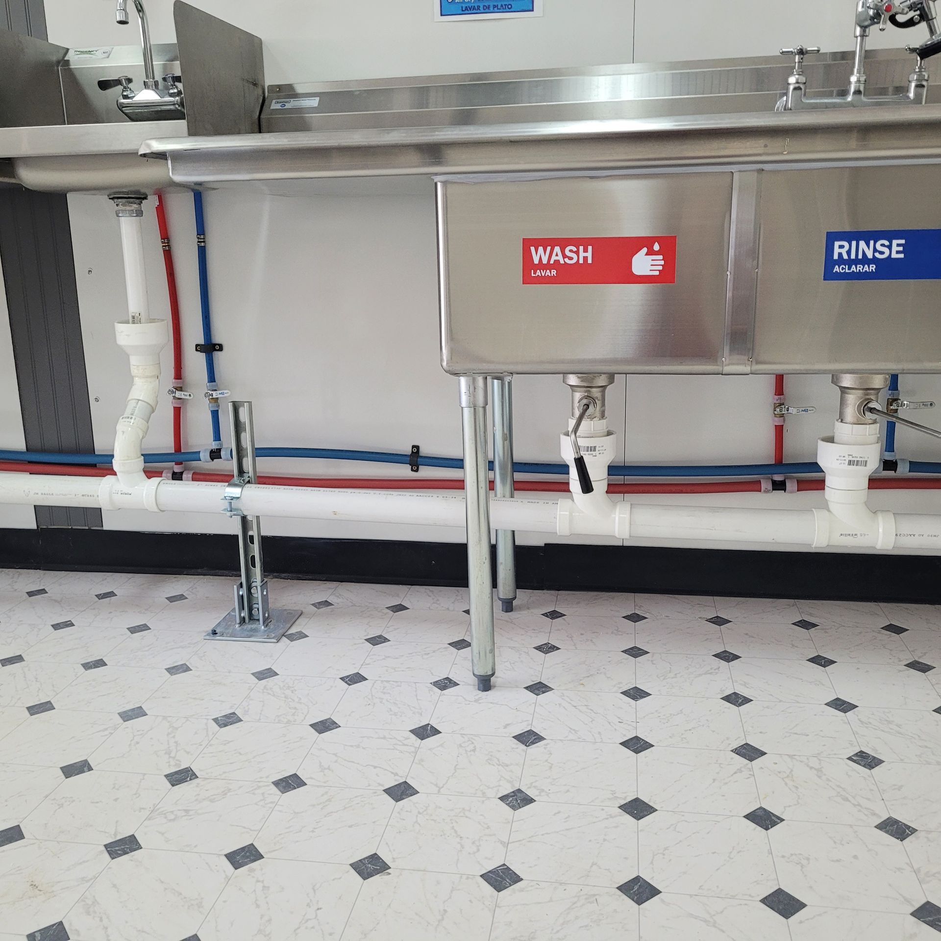 A stainless steel sink with a sign that says wash and rinse