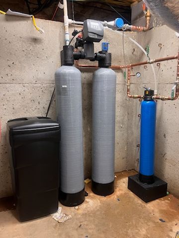 Two water filters are sitting next to each other in a basement.