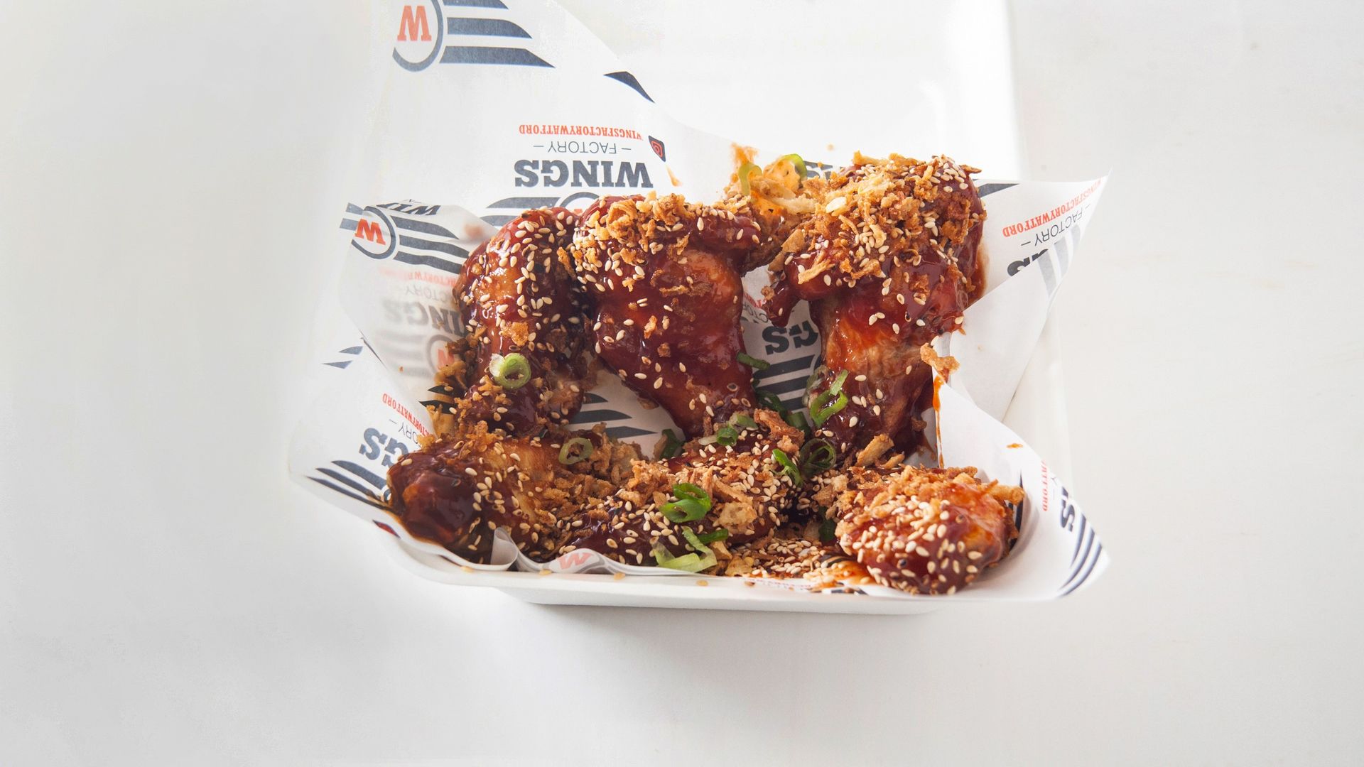 A styrofoam container filled with fried chicken wings on a table.