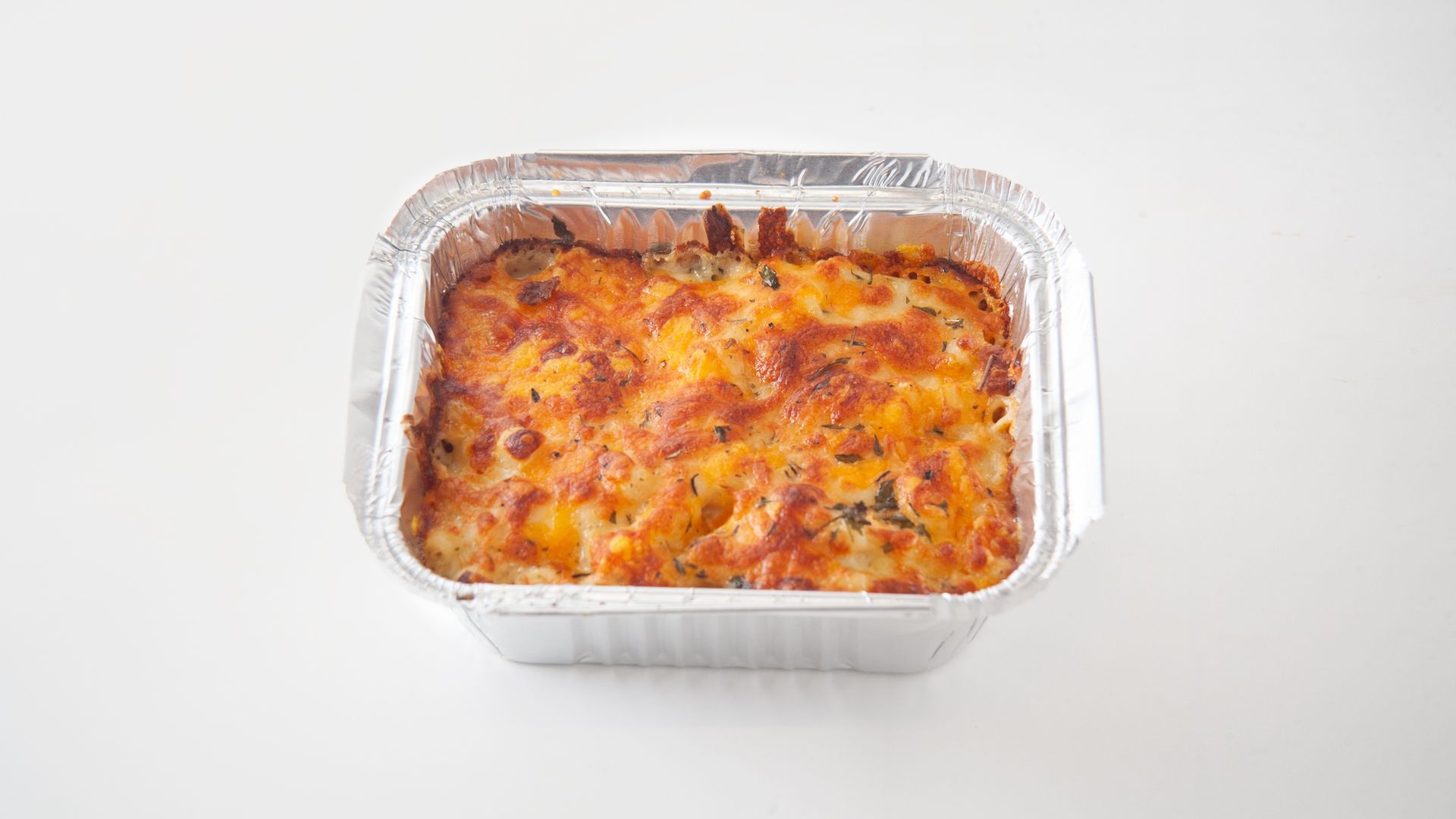 Aluminum foil container filled with a casserole on a white surface.