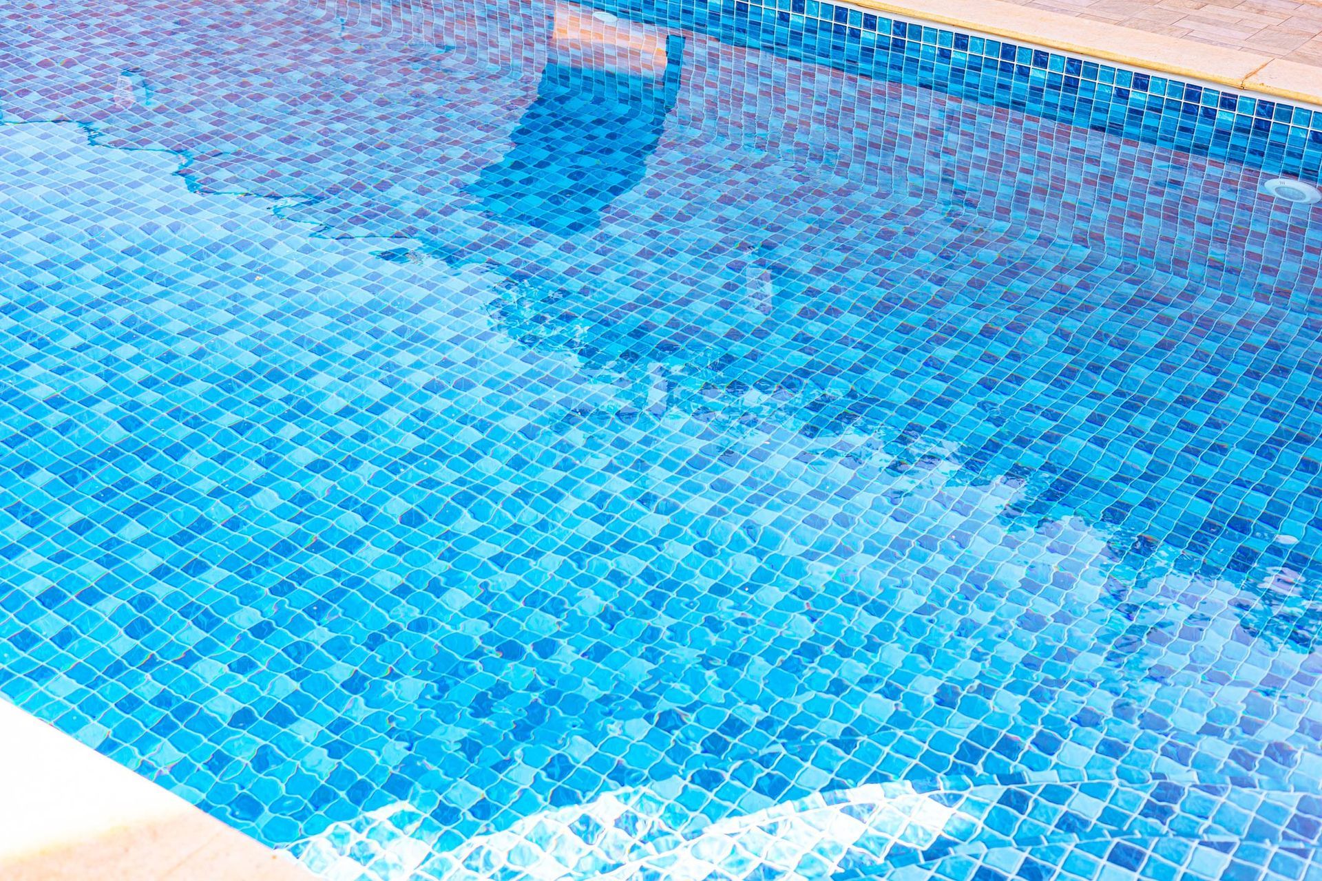 Blue tiled swimming pool reflecting sky.