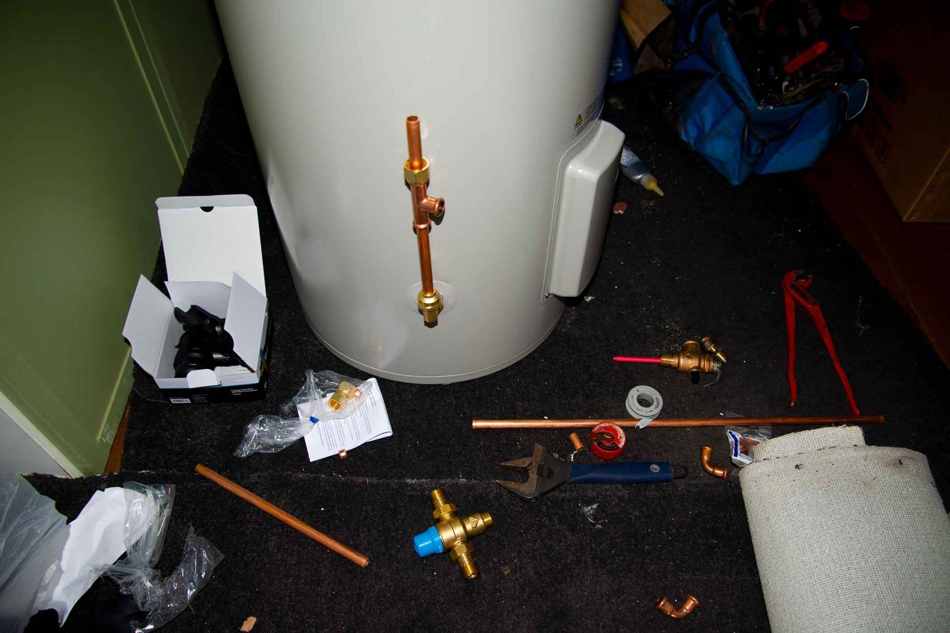 A water heater is being repaired on the floor