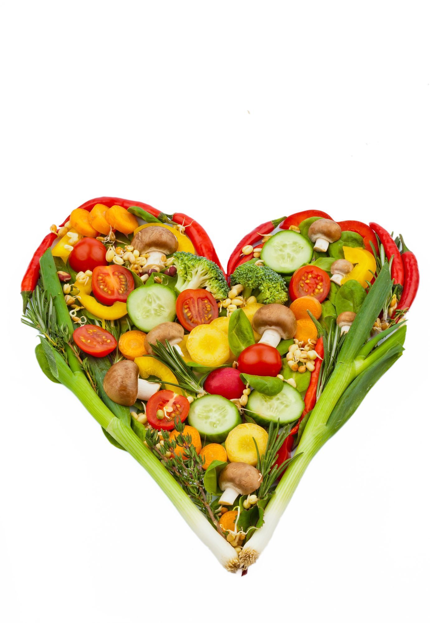 Heart shape made of fresh, colorful vegetables: tomatoes, peppers, cucumbers, mushrooms, and greens.