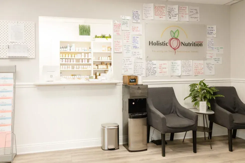 Reception area of a nutrition clinic with counter, waiting chairs, water cooler, and logo with notes on the wall.