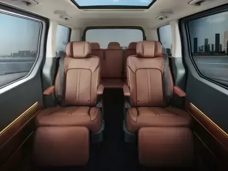 The interior of a minivan with brown leather seats and a skylight. Staria