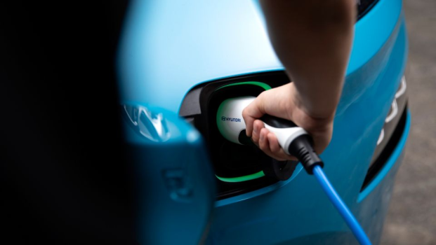 A person is charging a blue electric car with a hose.