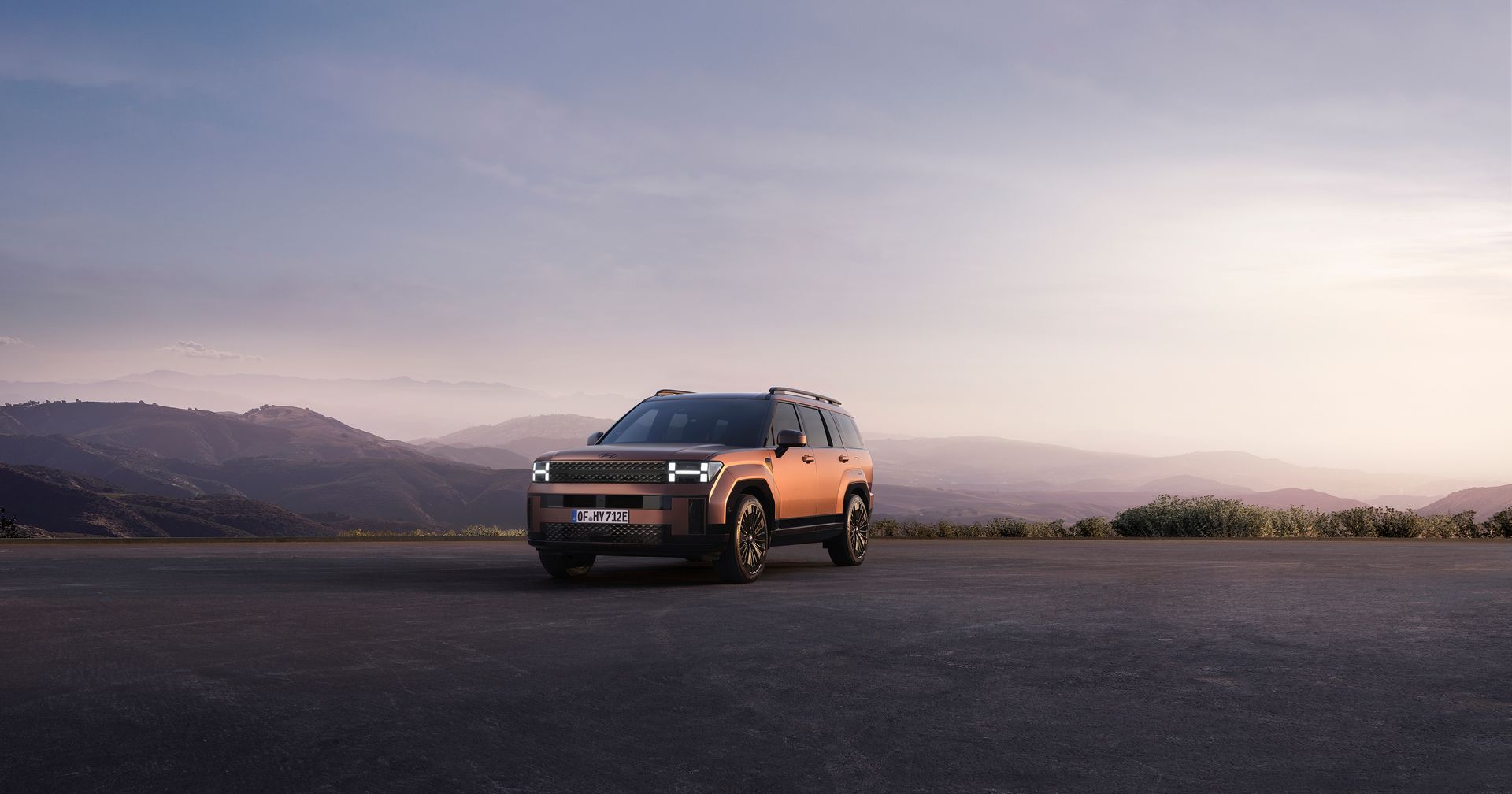 A car is parked on the side of a road with mountains in the background.