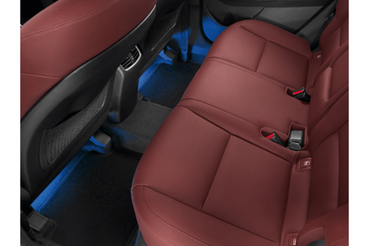 The back seat of a car with red leather seats and blue lights.