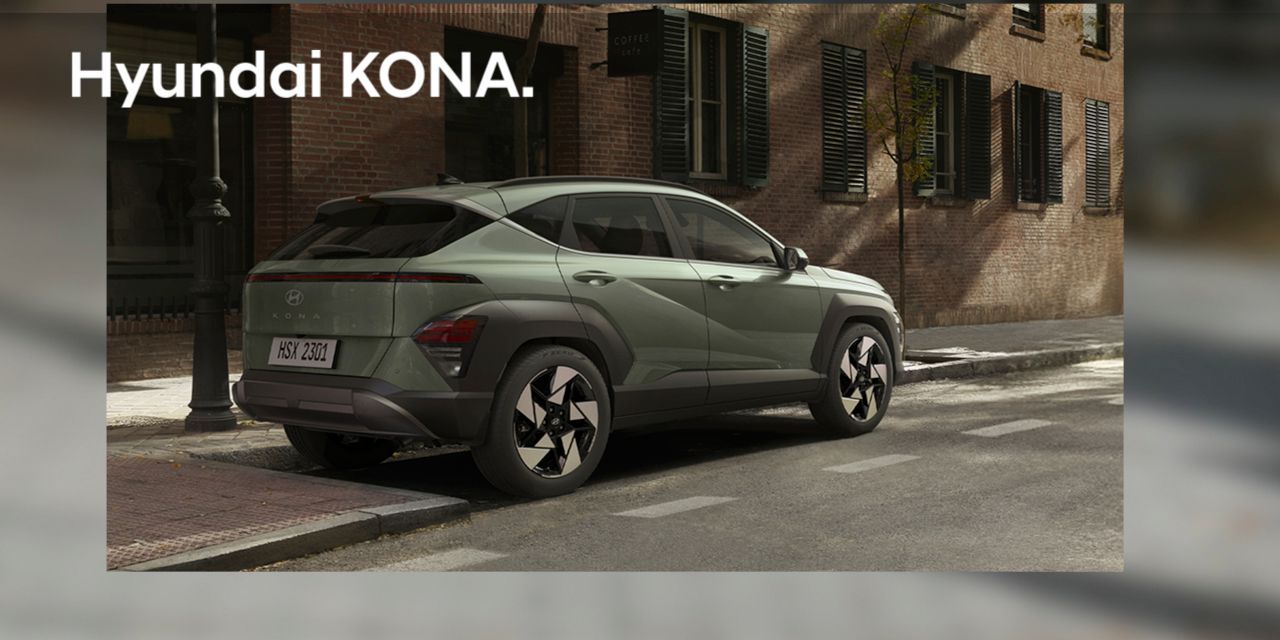 A yellow hyundai kona is parked in front of a building.