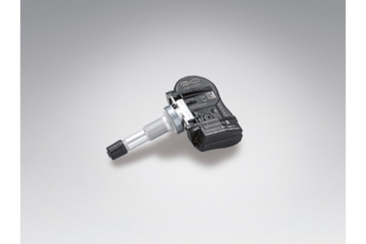 A black tire pressure sensor is sitting on a white surface.