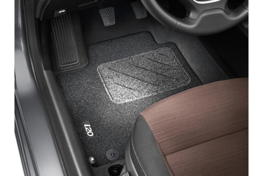 The interior of a car with a steering wheel and a carpeted floor mat.