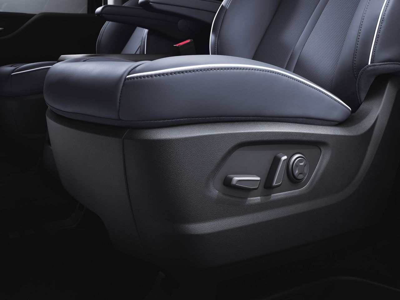 A close up of a car seat with a button on it Staria