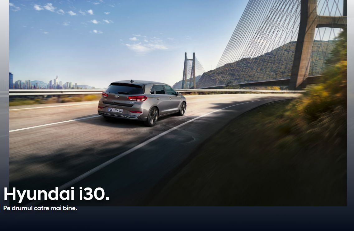 A hyundai i30 is driving down a highway next to a bridge.