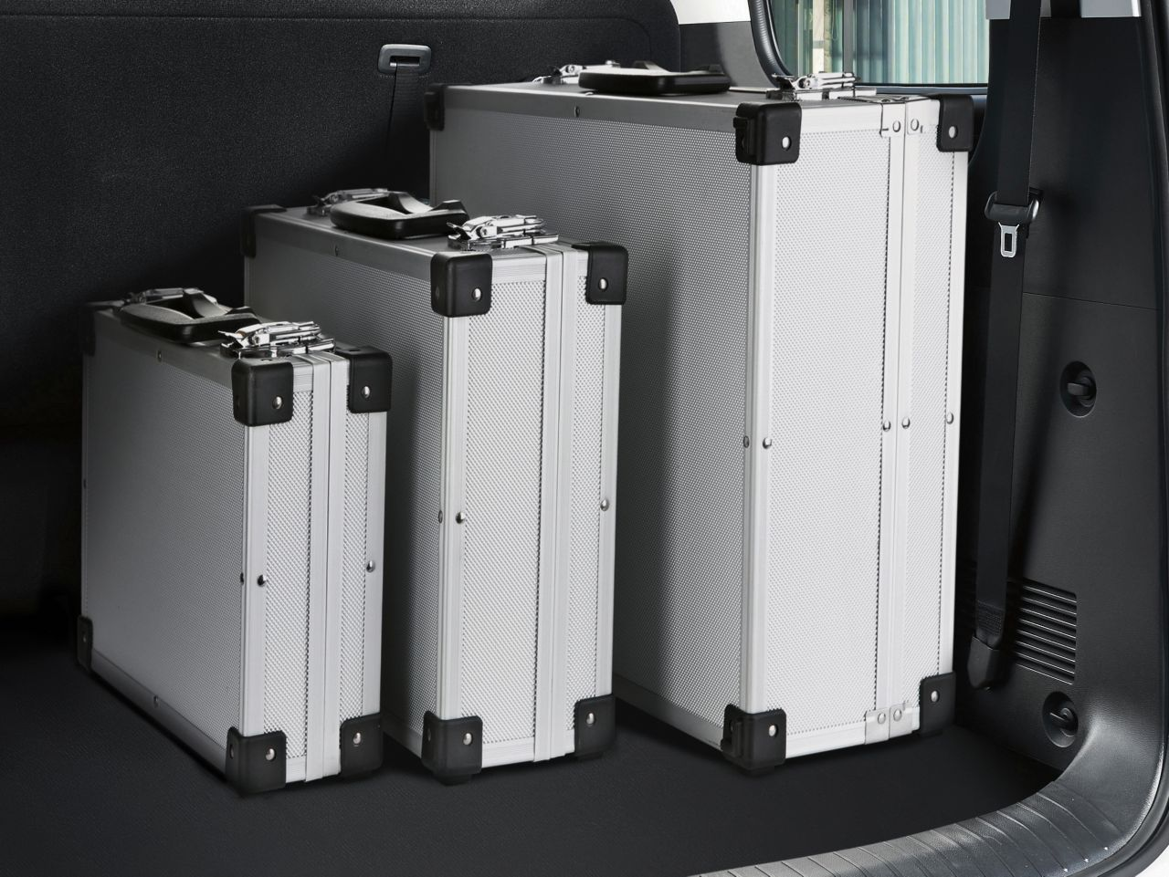 Three silver suitcases are in the back of a car Staria