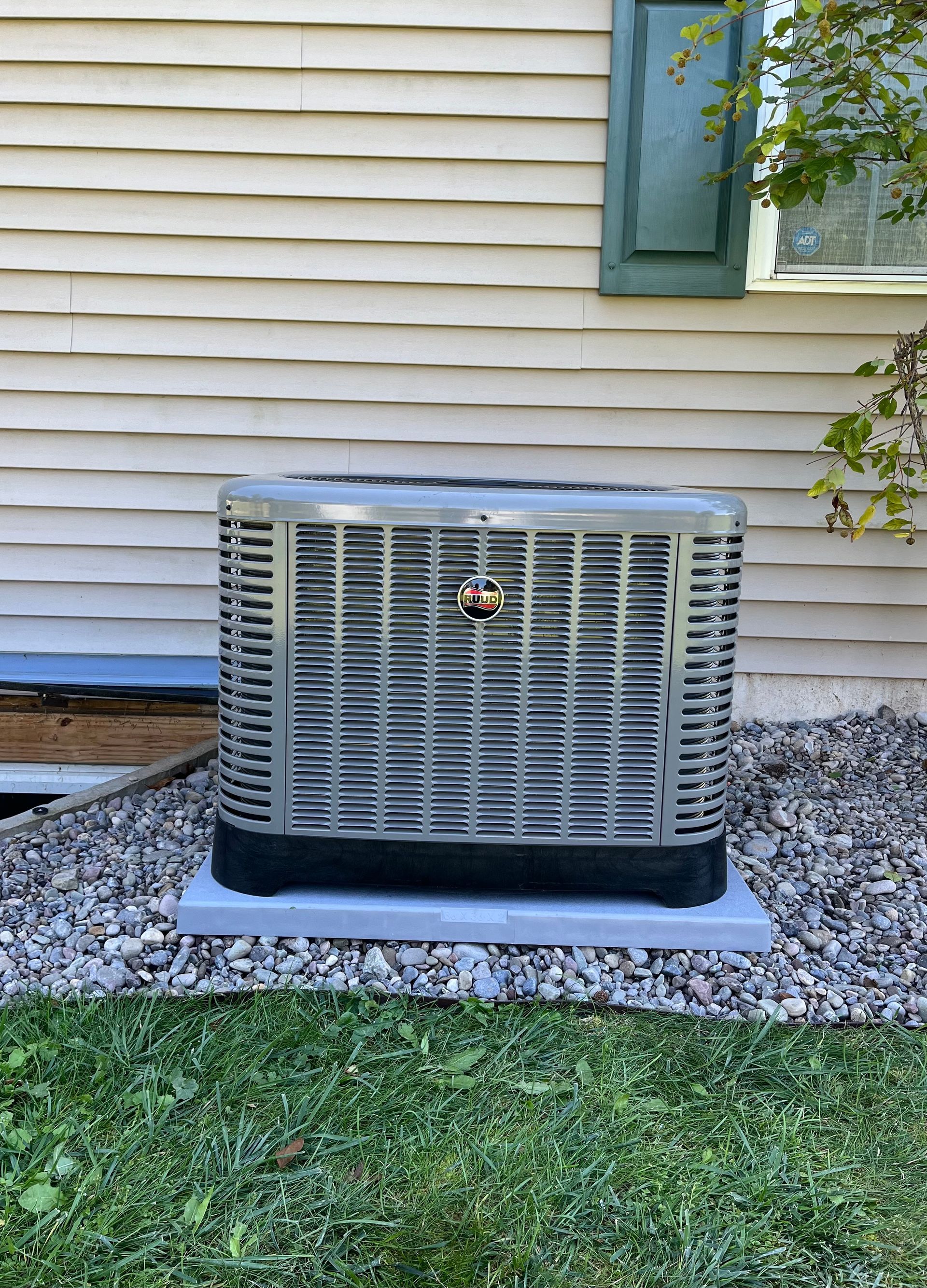 A mitsubishi electric air conditioner is sitting outside of a house.