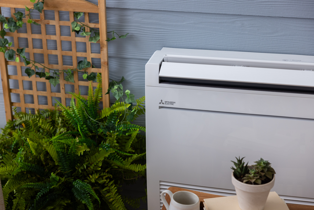 A white air conditioner is sitting on a table next to a potted plant.