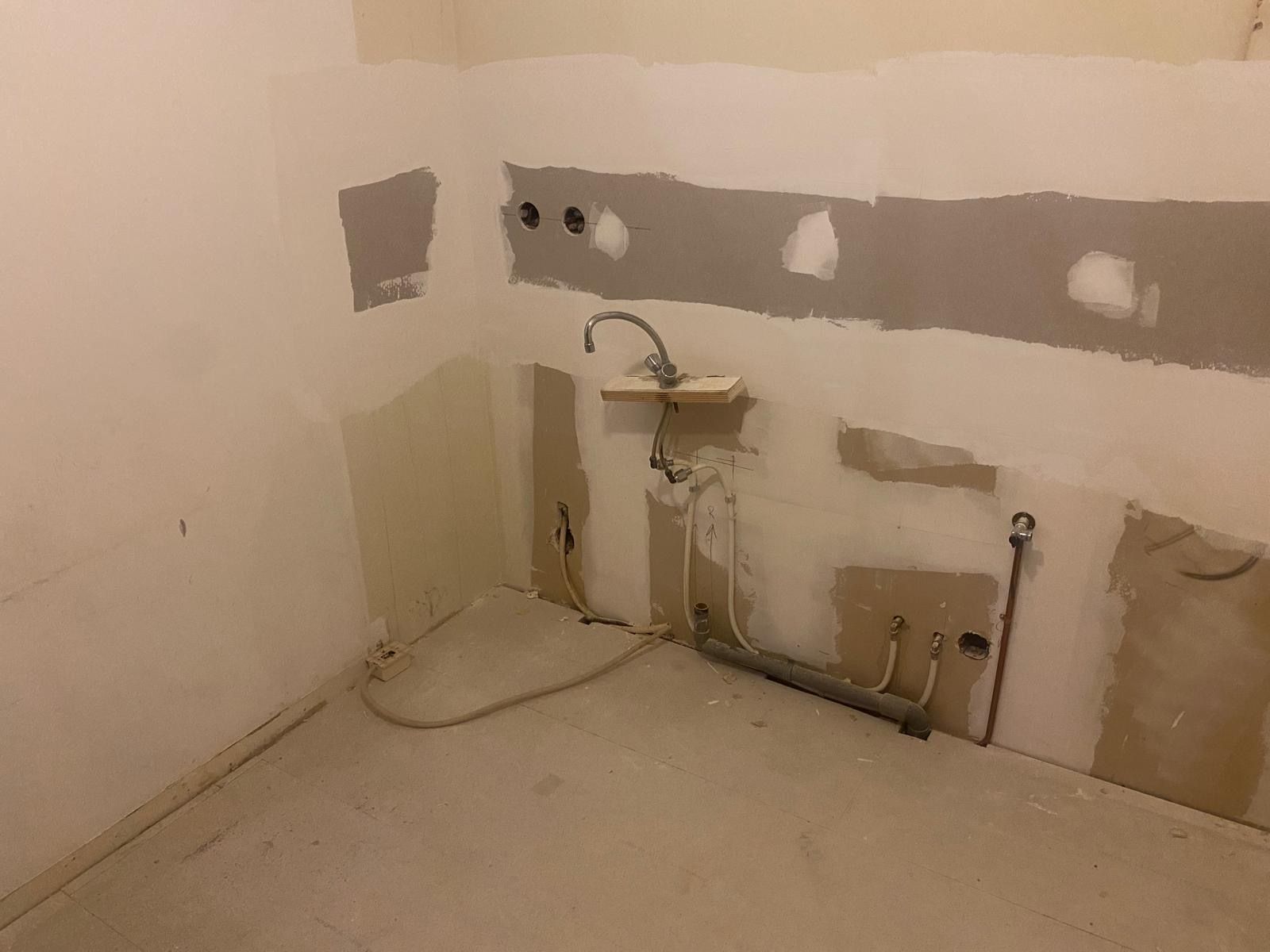 Voorbereiding van een keukenrenovatie met zichtbare aansluitingen en sloopwerkzaamheden